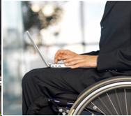 Person sitting in a wheelchair using a laptop computer.