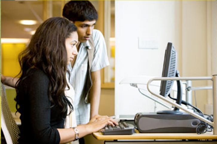 A photo of two students, one male and one female, working together on a computer, shown here to facilitate discussion over how a web author might describe this image. 